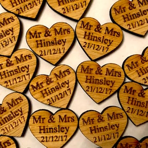 Op de afbeelding: Een close-up van houten hartvormige bruiloftsfavoren met de tekst "Mr & Mrs Hinsley 21/12/17" gegraveerd op elk.