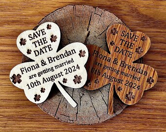 May include: Two wooden shamrock-shaped save the date magnets with the text "Save the Date" and "Fiona & Brendan are getting married 10th August 2024".