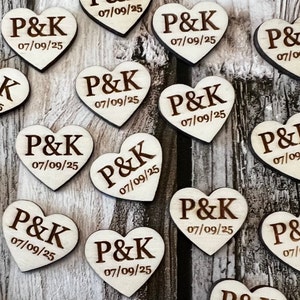 May include: Wooden heart-shaped wedding favors with the initials "P&K" and the date "07/09/25" engraved on them.
