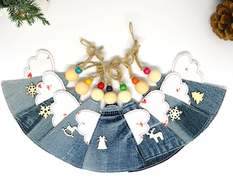 May include: A set of 8 denim Christmas ornaments with white wings and wooden cutouts of a snowflake, Christmas tree, reindeer, bell, and a rocking horse. Each ornament is strung with colorful wooden beads and twine.