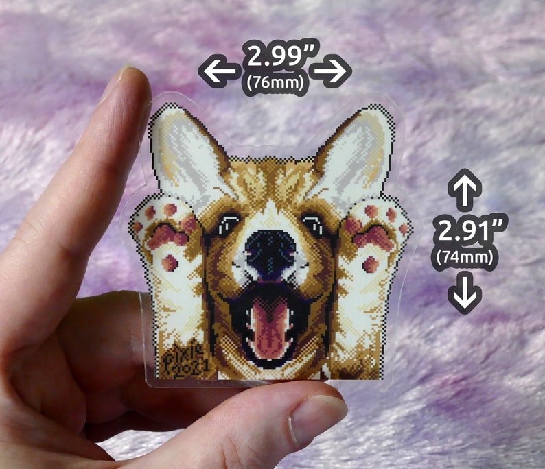 May include: A clear sticker with a pixelated image of a corgi dog with its paws up, looking at the camera with its tongue sticking out. The sticker is 2.99 inches wide and 2.91 inches tall. The sticker has the text "PIKIR 2021" in the bottom left corner.