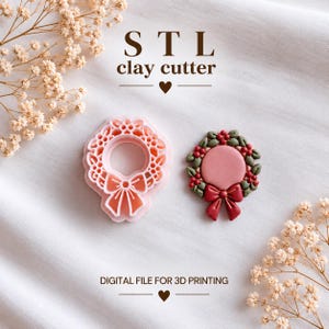 以下が含まれることがあります： リボン付きのクリスマスリースの形をしたライトピンクのSTL粘土カッターと、緑、赤、ピンクの粘土で作られた完成品のリースオーナメント。テキストには「STL clay cutter」および「DIGITAL FILE FOR 3D PRINTING」と記載されています。