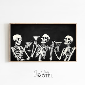 May include: Framed black and white art print showing three skeletons raising martini glasses. The skeletons are depicted in detail, with visible rib cages and skulls. The text "Good Vibes Motel" is at the bottom of the print.