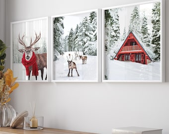 May include: Three framed winter scenes with a red cabin, a reindeer, and a deer wearing a red scarf. The frames are white and the images are printed on white paper.