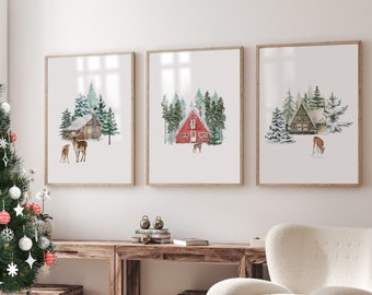 May include: Three framed watercolor paintings of winter scenes with cabins and deer. The paintings are hung on a white wall above a wooden table and a white armchair.