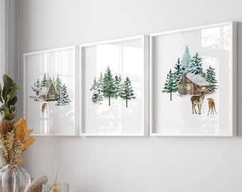 May include: Three white framed watercolor paintings of a winter forest scene with a cabin and deer. The paintings are hanging on a white wall above a wooden cabinet.