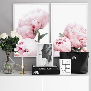 Puede incluir: Dos impresiones enmarcadas de peon&iacute;as rosas, una foto en blanco y negro de Kate Moss, una bolsa de mano negra con un logotipo dorado y una impresi&oacute;n enmarcada de la palabra "LOVE" en blanco y negro.