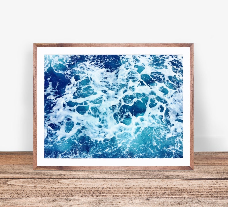 May include: A close-up photo of blue ocean water with white foam and bubbles. The water is a deep blue color and the foam is white and fluffy.