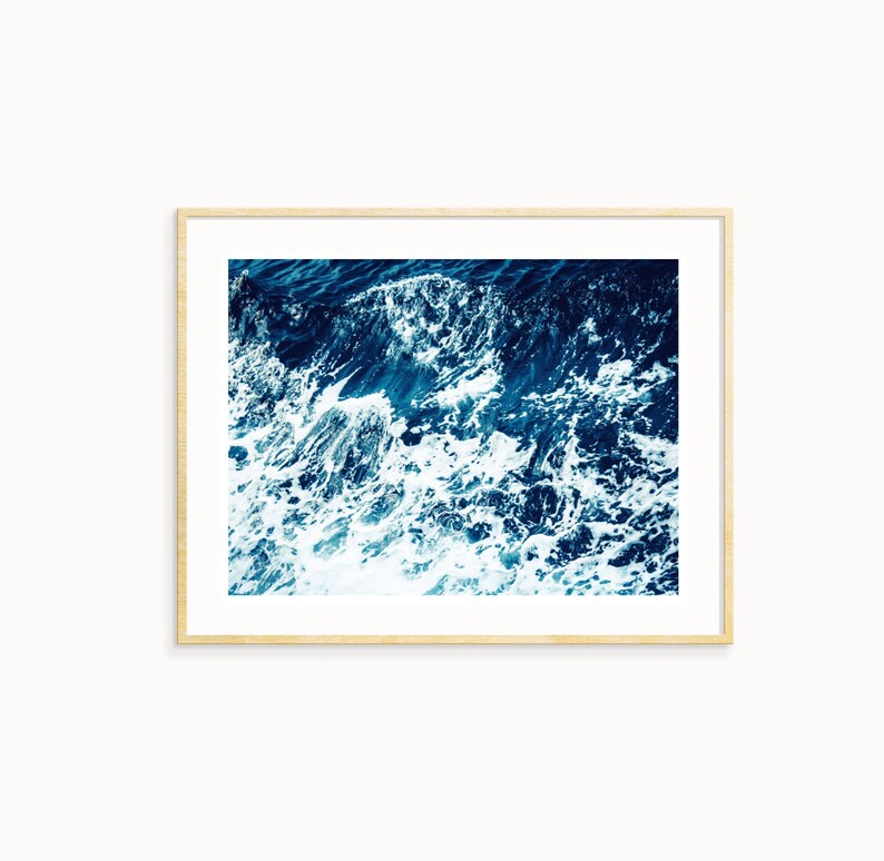May include: A close-up photograph of a blue ocean with white foamy waves crashing.