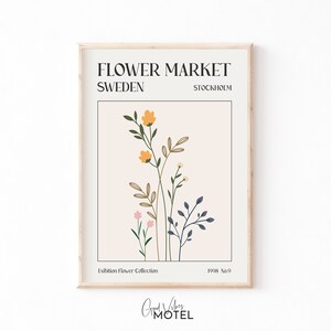 May include: A minimalist poster with a floral illustration in shades of yellow, pink, green, and blue. The poster has the text "FLOWER MARKET SWEDEN STOCKHOLM Exhibition Flower Collection 1998 No.9 Good Vibes Motel" printed on it.