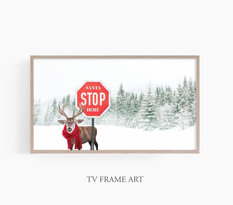 Puede incluir: Una se&ntilde;al de stop roja con las palabras "Santa Stop Here" en texto blanco, con un ciervo con una bufanda roja de pie frente a ella en un entorno de bosque nevado.