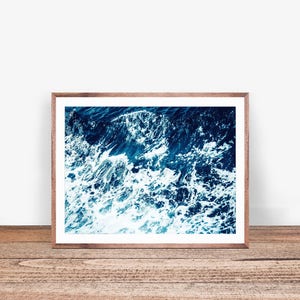 May include: A framed photograph of a close-up of ocean waves crashing, with white foam and deep blue water.