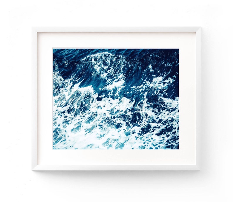 May include: A framed photograph of a close-up of ocean waves crashing, with white foam and blue water.