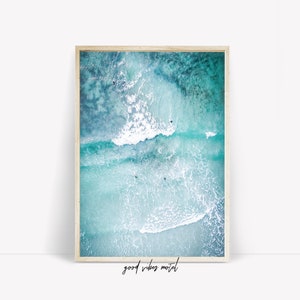 May include: An aerial view of turquoise ocean water with white foamy waves crashing. The water is clear and you can see people swimming and surfing in the waves.
