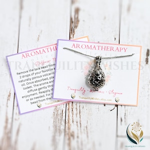 May include: A silver aromatherapy diffuser necklace with a detailed design. The necklace is on a white card with the text "Tranquility. Wellness. Elegance" and the website address "TranquilityWishes.etsy.com".