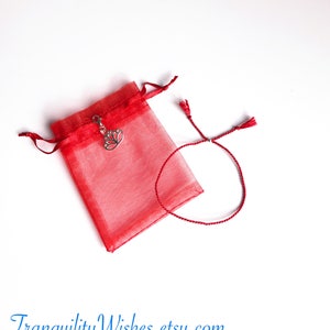 May include: Red string bracelet with a silver lotus charm, packaged in a red organza bag. Tranquility Wishes.etsy.com