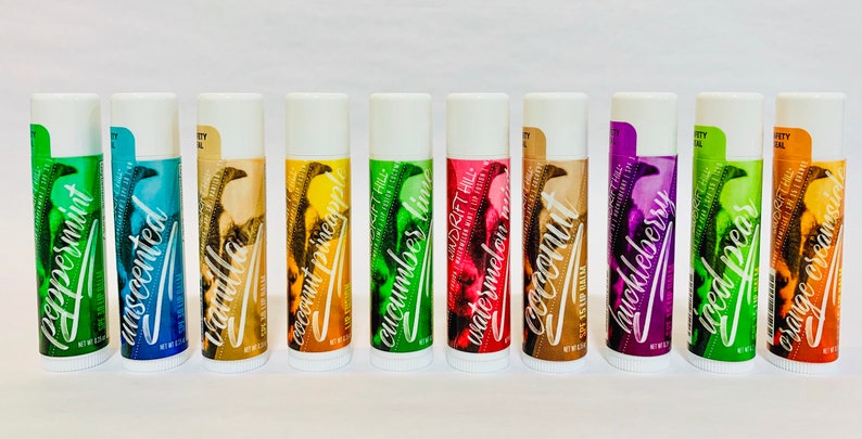 May include: Ten different flavored lip balms in white tubes with colorful labels. The flavors are Peppermint, Unscented, Vanilla, Coconut Pineapple, Cucumber Lime, Watermelon, Coconut, Huckleberry, Iced Pear, and Orange Creamsicle.