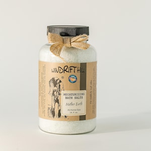 May include: A glass jar of white bath salts with a brown label that reads "WINDRIFT HILL" and "MOISTURIZING BATH SALTS Mother Earth At-Home-Spa 16.9 oz.". The jar is tied with a brown twine bow.