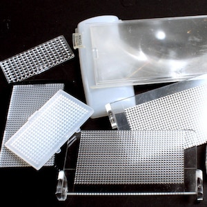 May include: A collection of clear plastic diffusers with a grid pattern. The diffusers are various sizes and shapes, and some have a smooth surface.