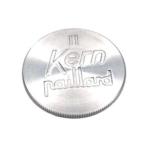 Puede incluir: Un disco de metal plateado con el texto "Kern Paillard" grabado en él.