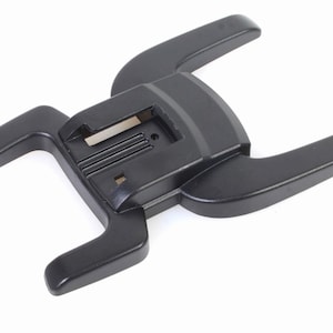 May include: Black plastic flash bracket with a U-shaped design and a central mounting plate. The bracket has two arms that extend out from the mounting plate.