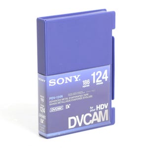 Puede incluir: Una cinta de video Sony DVCAM azul, etiquetada "PDV-124N" con el texto "Advanced Metal Evaporated Tape" y "DVCAM D* para HDV".