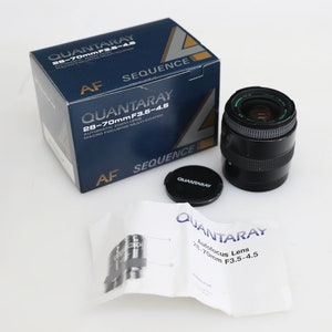 May include: A black and silver autofocus zoom lens with the text "QUANTARAY 28-70mm F3.5-4.5" on the lens barrel and box. The lens is packaged in a blue box with the text "QUANTARAY 28-70mmF3.5-4.5" and "AF SEQUENCE" on the box.