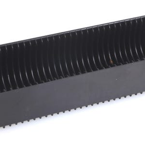 May include: A black plastic film slide storage container. The container has a rectangular shape with a series of curved dividers inside. The bottom edge has small, evenly spaced teeth.