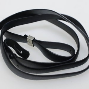 May include: A black leather camera strap with a silver metal buckle.