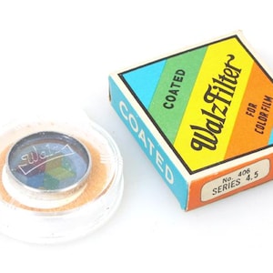May include: A vintage Walz Filter No. 406 Series 4.5 coated filter for colour film in a yellow, orange, green, and blue box. The filter is in a clear plastic case with a silver rim.