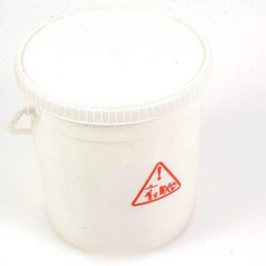 May include: A white plastic bucket with a lid and a handle. A red hazard symbol is printed on the side. The bucket is cylindrical and appears to be empty.