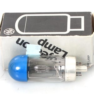 May include: A blue glass vacuum tube with a metal base and a blue cap. The tube is in its original box, which is labeled "GE Lamp".
