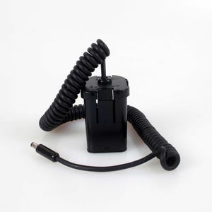 May include: A black rectangular battery pack with a coiled cord extending from the top and a straight cable ending in a cylindrical power connector. The unit features a smooth plastic casing and a secure attachment point for the integrated power cable.