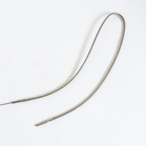 May include: A pair of silver-colored, flexible, braided cables with a green outer sheath and small metal connectors at each end.