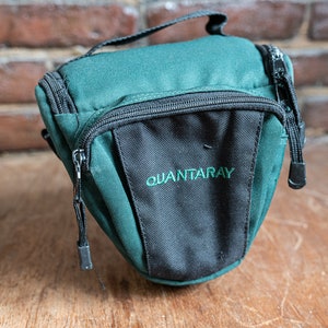 May include: A green and black camera bag with the word "QUANTARAY" printed on the front.