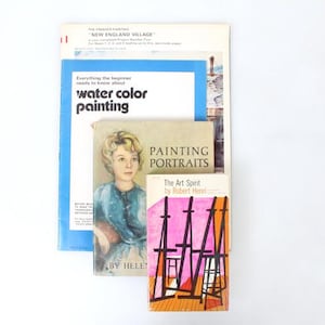 Könnte beinhalten: Ein Stapel alter Kunstbücher, darunter "Water Color Painting" und "Painting Portraits". Die Bücher haben farbenfrohe Einbände und Titel, die sich auf Kunstunterricht und -techniken konzentrieren. Die Bücher liegen auf einer weißen Oberfläche.