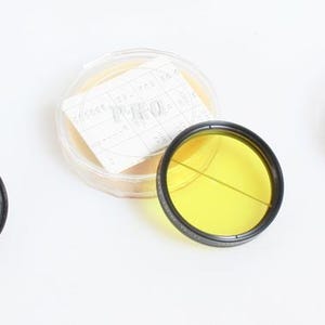 Könnte beinhalten: Drei Objektivfilter für Kameras, einer gelb, einer schwarz und einer klar, mit dem Wort "PRO" auf dem klaren Filter.