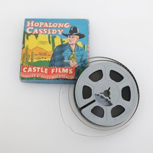 Può includere: Un rotolo di pellicola 8 mm vintage con una striscia di pellicola in bianco e nero. Il rotolo è etichettato "Hopalong Cassidy" e "Castle Films" con il testo "Prodotto da United World Films Inc."