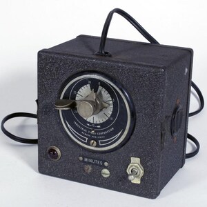 May include: A dark gray industrial timer with a textured metal housing, a circular dial marked from 0 to 30, and a central knob. The face reads Industrial Timer Corporation, Newark, New Jersey, and Minutes. It includes a toggle switch and a power cord.