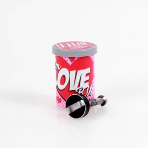 May include: A cylindrical film canister with a gray lid and a red label featuring a large heart graphic, white text reading "I'm LOVE BW", and a small black and silver metal film spool component positioned in front of the container on a white surface.