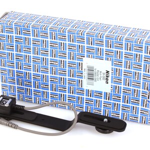 May include: A Nikon Multi-Flash Bracket Unit SK-E900 with a box featuring a blue and white pattern with the Nikon logo. The bracket is black with a silver cable and a flash mount. The box has a white label with product information.
