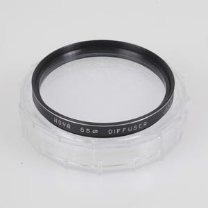 May include: A Hoya 55mm diffuser filter in a clear plastic case. The filter has a black ring with white text that reads "HOYA 55ø DIFFUSER". The clear case has an octagonal shape.
