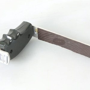 May include: A black and silver hand-held tool with a wooden handle and a trigger. The tool has a strap for added grip.