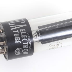 May include: An RCA Electron Tube, a vintage electronic component. The tube has a black base with the text "RCA ELECTRON TUBE" in white. The clear glass enclosure houses internal components. The tube has several pins.