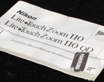 May include: A white instruction manual for a Nikon Lite Touch Zoom 110 camera. The manual has the word "Nikon" at the top, with "Lite Touch Zoom 110" printed below. The word "Panorama" is printed on the top right corner.