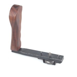 Könnte beinhalten: Ein Kameragriff mit einem dunkelbraunen Holzgriff und einer schwarzen Metallbasis. Der Griff ist ergonomisch geformt. Die Basis hat Schrauben und ein Rad zur Befestigung an einer Kamera.