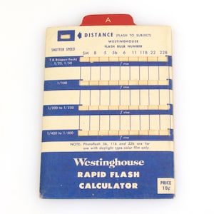 Puede incluir: Una guía de cálculo de flash rápido Westinghouse azul y blanca con una pestaña roja etiquetada como "A". La guía tiene un cuadro con velocidades de obturación y números de bombilla de flash.