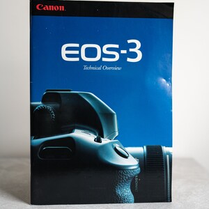 May include: A blue and black Canon EOS-3 Technical Overview booklet with a black and silver camera on the cover.