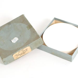 Może przedstawiać: Biały, okrągły papierowy krążek w jasnoniebieskim pudełku. Pudełko ma etykietę z napisem "100 Kręgów 12,5 cm Średnio 100 na Krąg 500 gramów".