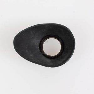 May include: A black rubber eyecup for a camera, with an oval shape and a circular opening in the center. The eyecup is designed to fit over the viewfinder of a camera to block out light.